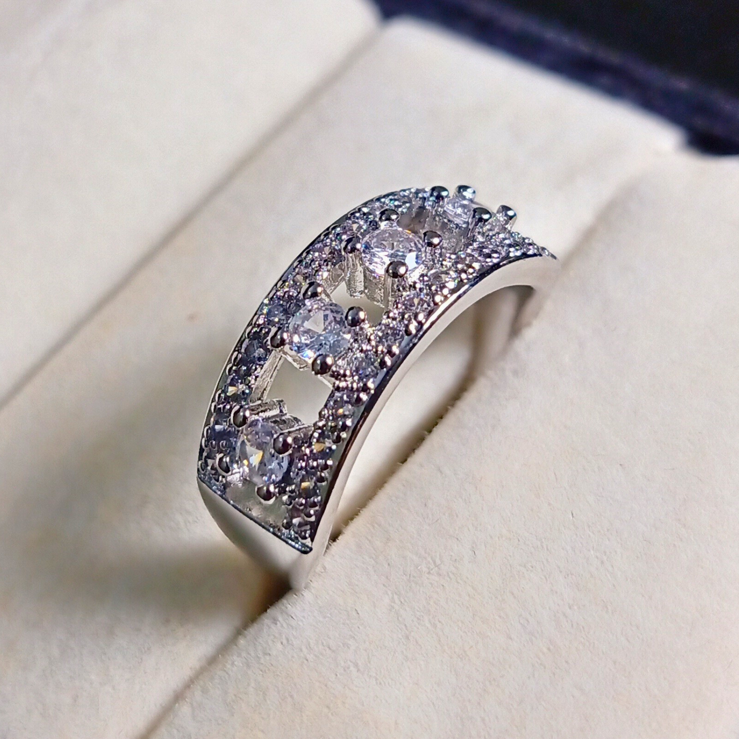 Silver ring with embedded stones on a soft beige background