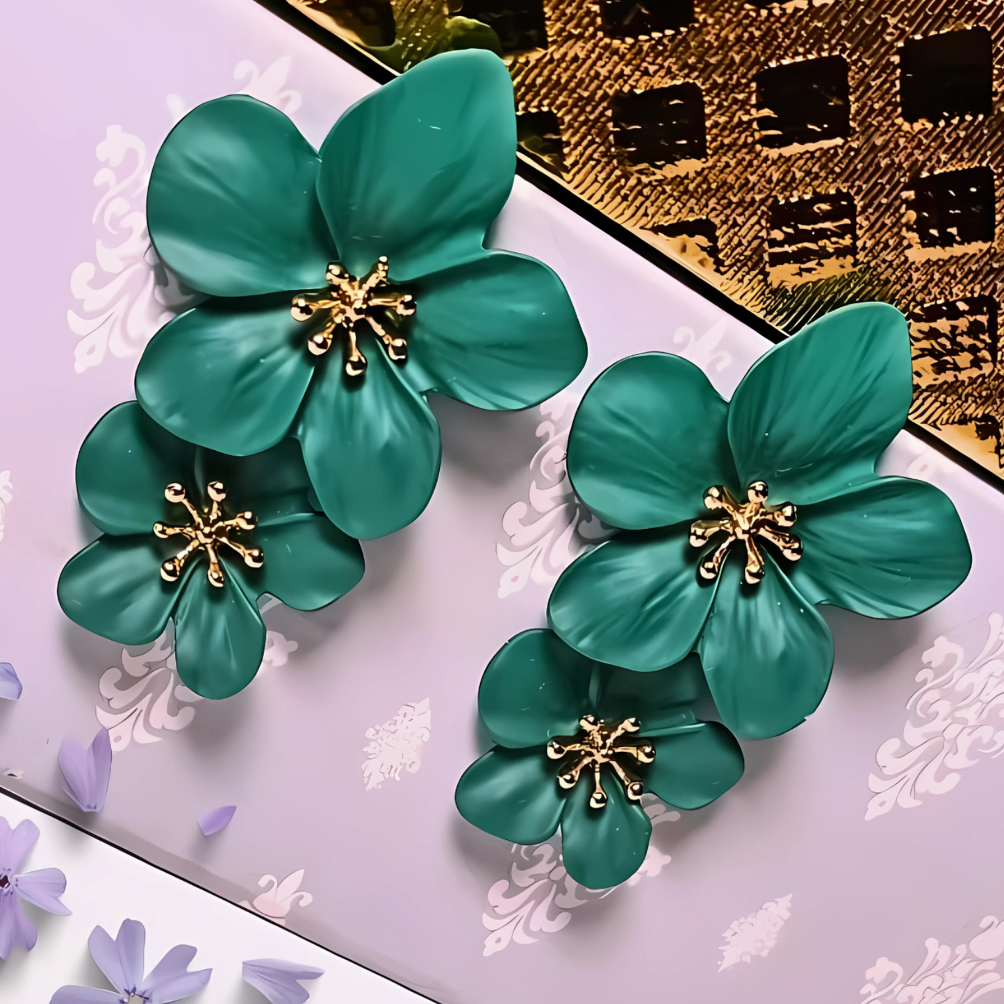 Green floral earrings with gold centers on a decorative background