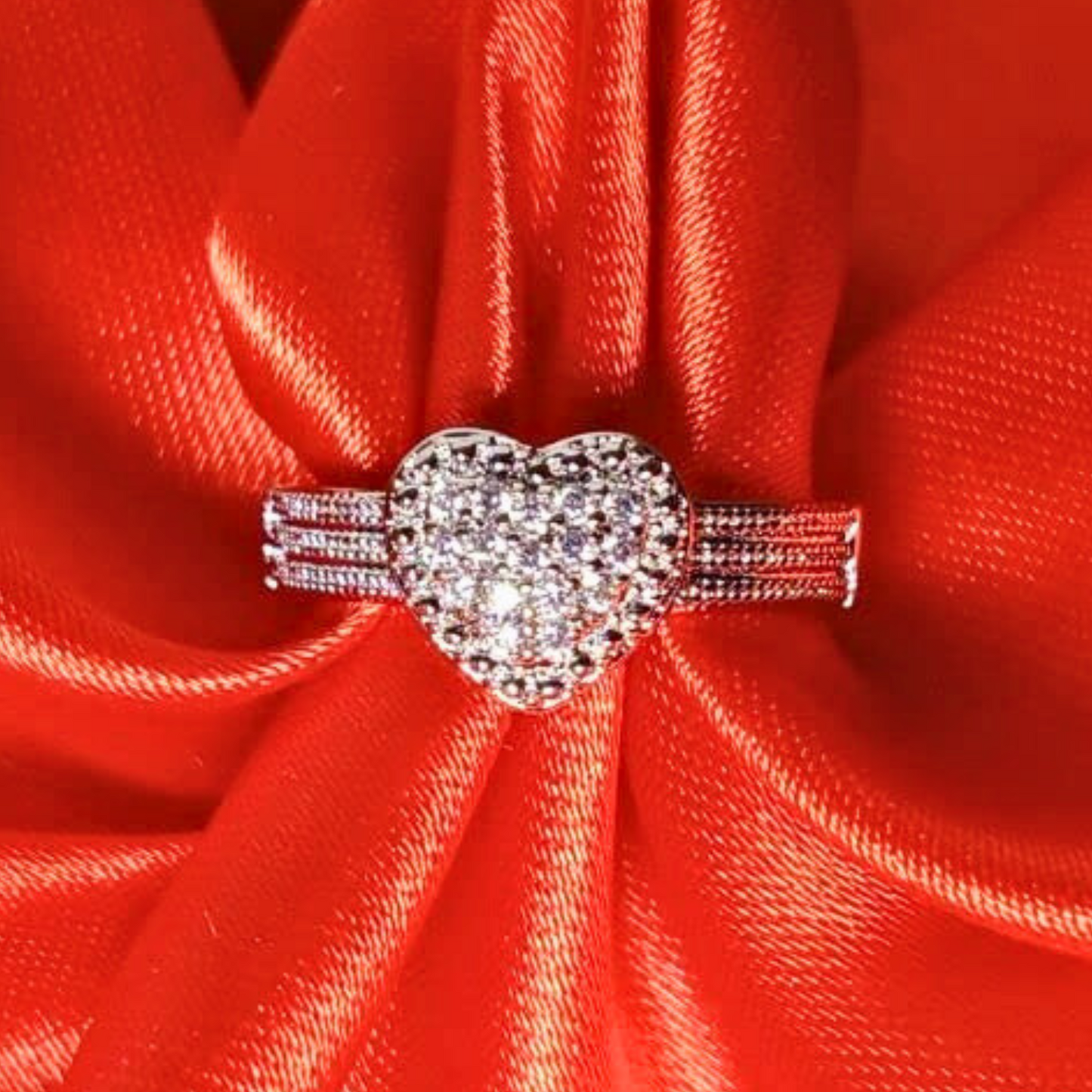 Silver heart-shaped ring on a red fabric background