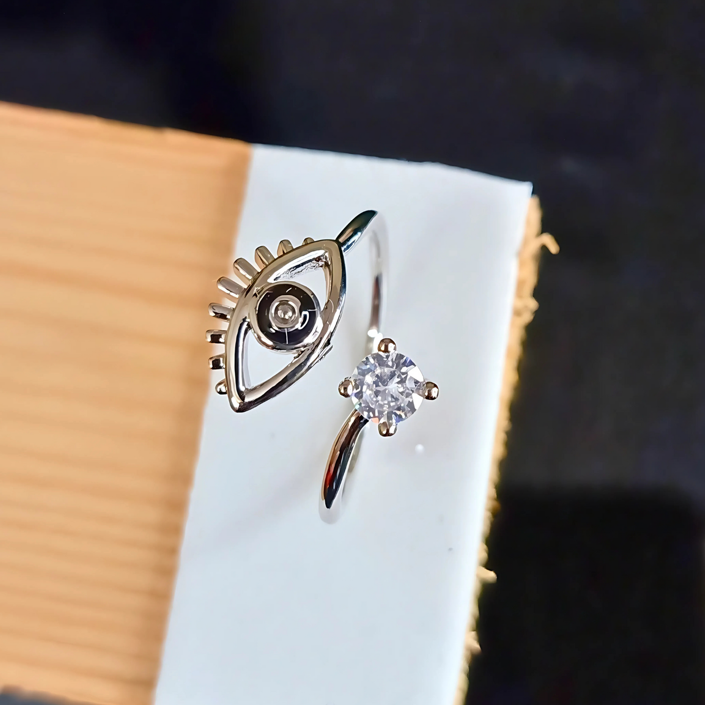 Silver color black eye design ring on a wooden surface