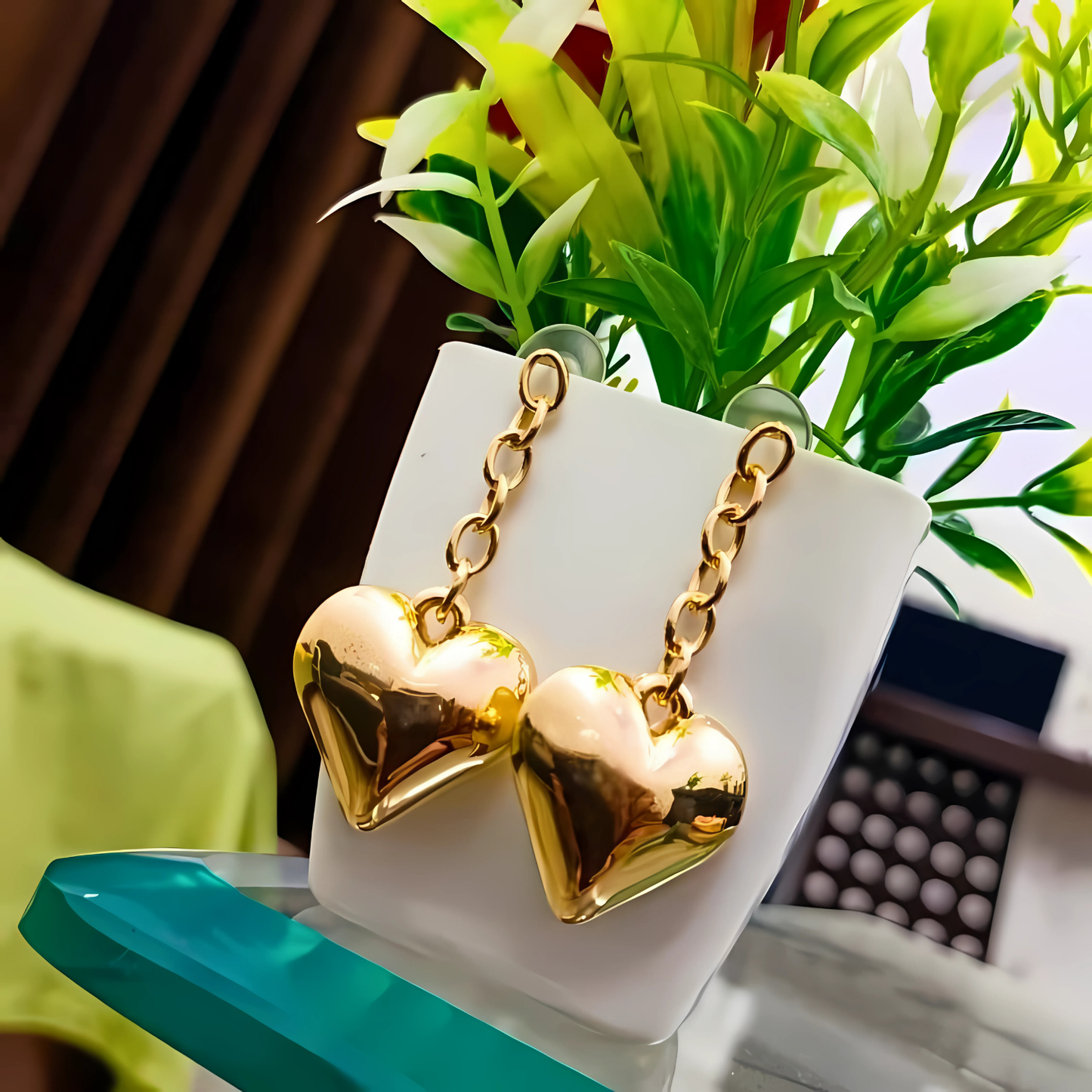 Gold heart-shaped earrings on a white stand with a blurred background