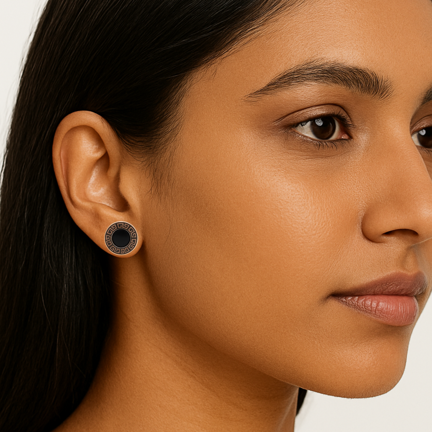 Close-up of a woman wearing a black and silver earring on a white background