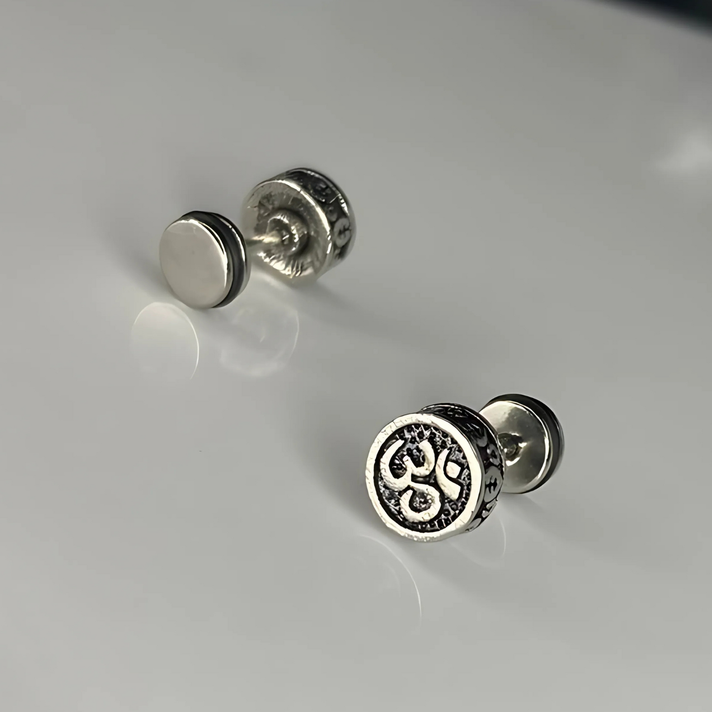 Pair of silver stud earrings on a light gray background