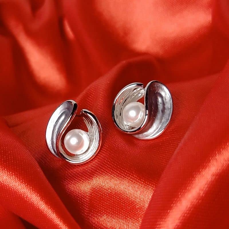 Silver earrings with pearls on a red fabric background