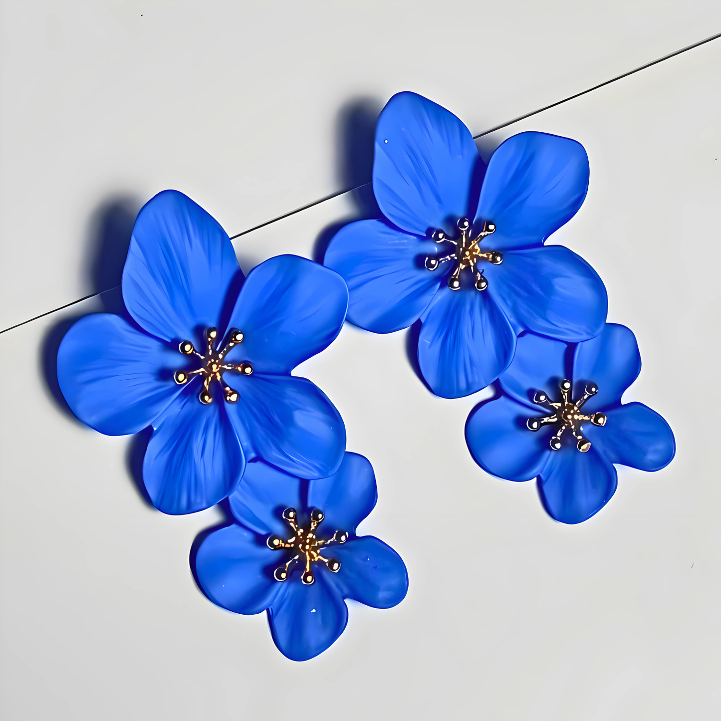 Blue flower-shaped earrings on a light gray background