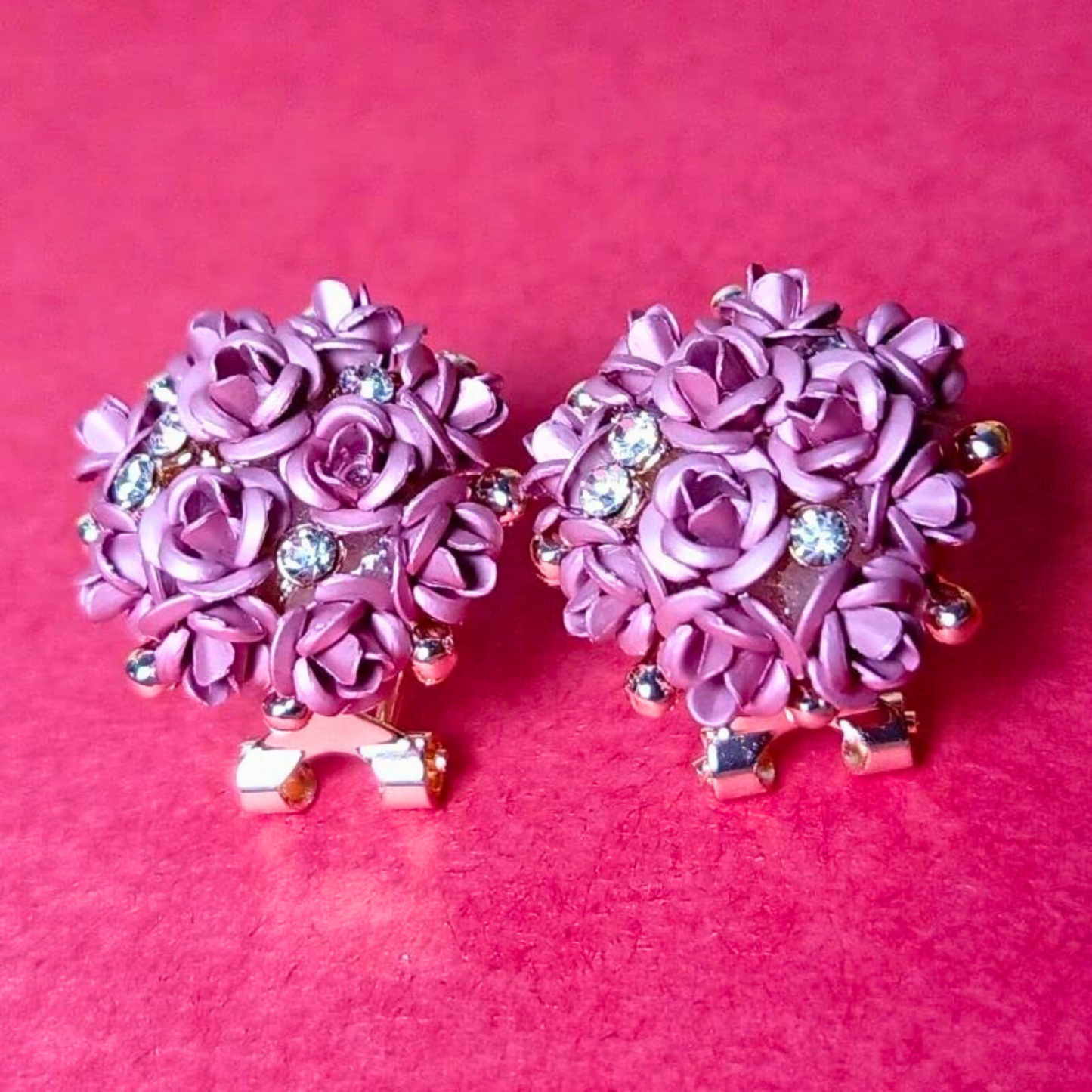 Pair of pink floral earrings with rhinestones on a pink background
