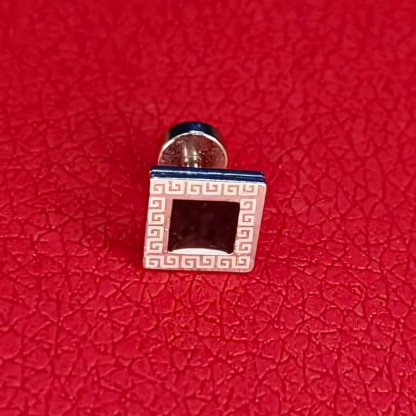 Cufflinks with a geometric design on a red textured background