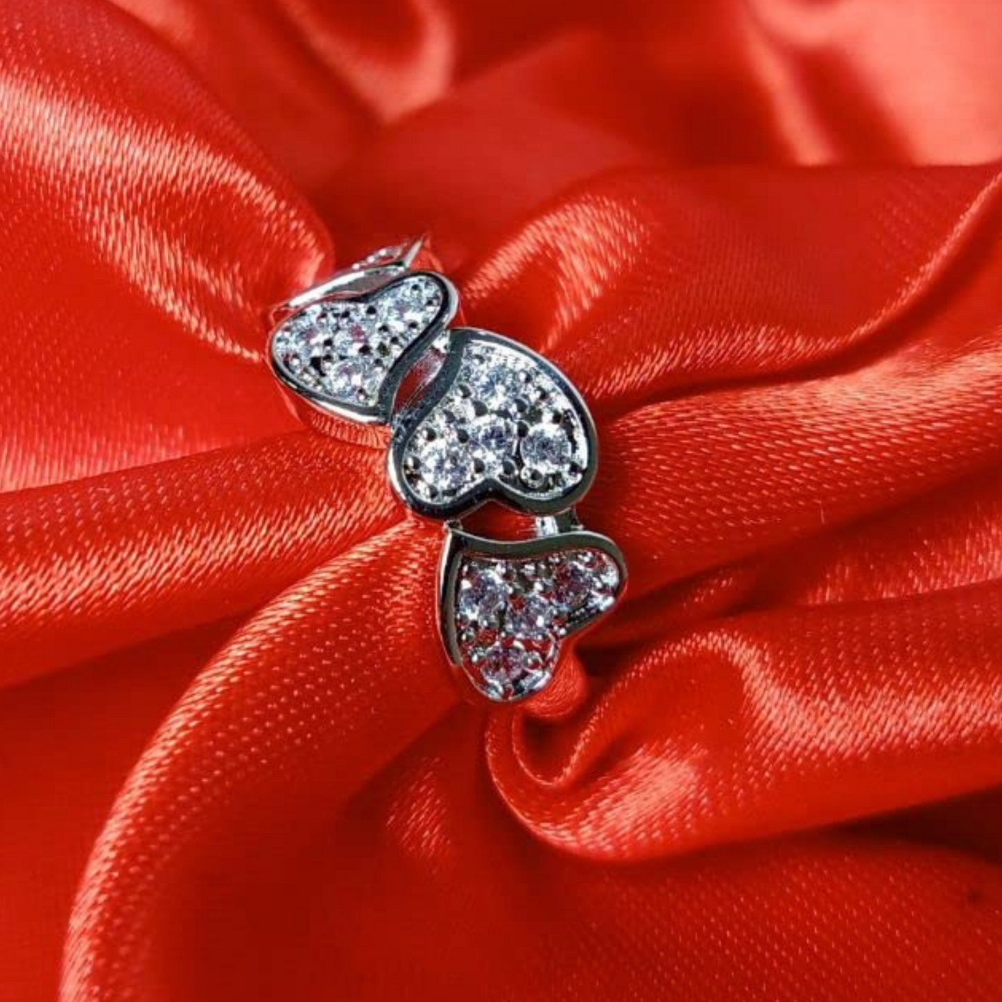 Heart-shaped earrings with clear stones on a red satin background
