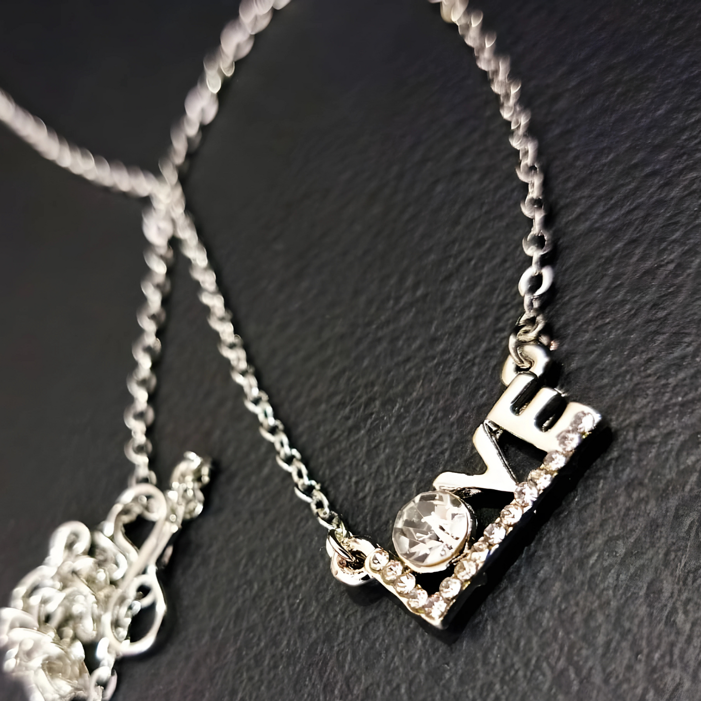 Silver necklace with a 'love' pendant on a dark textured surface