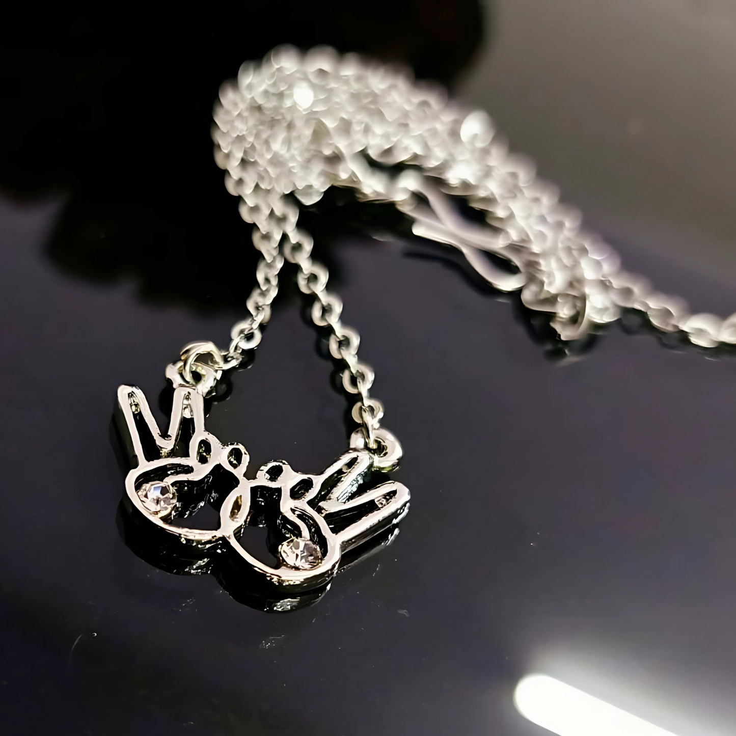 Silver necklace with a pendant on a reflective black surface