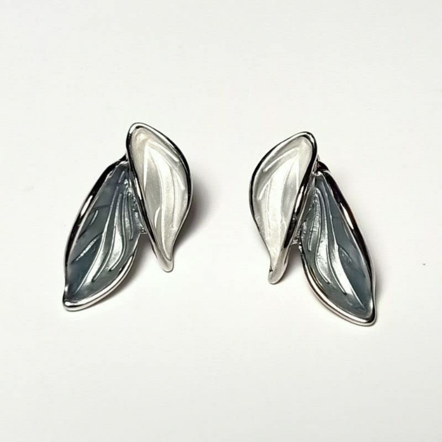 Pair of silver leaf-shaped earrings on a white background