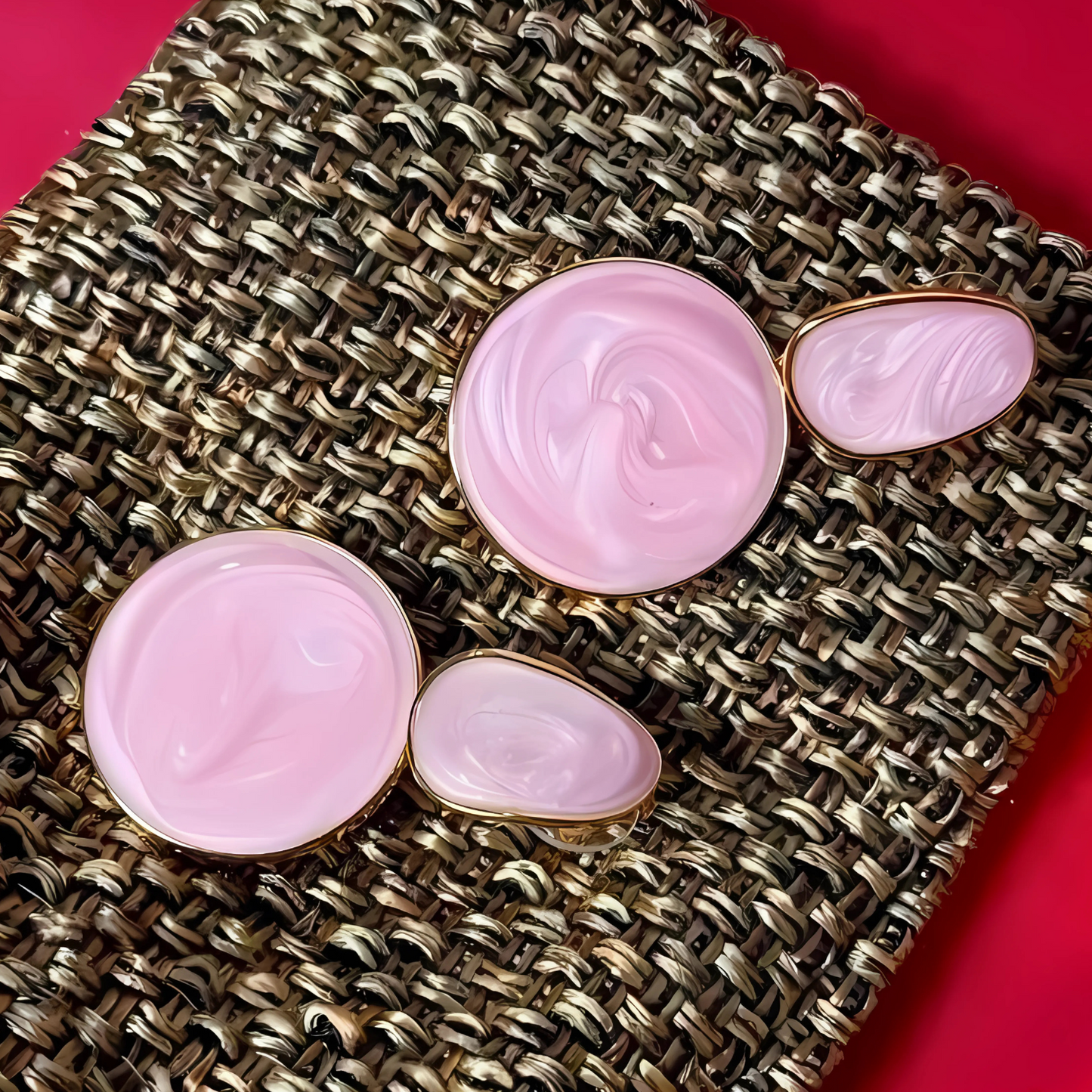 Set of pink earrings with gold accents on a textured surface