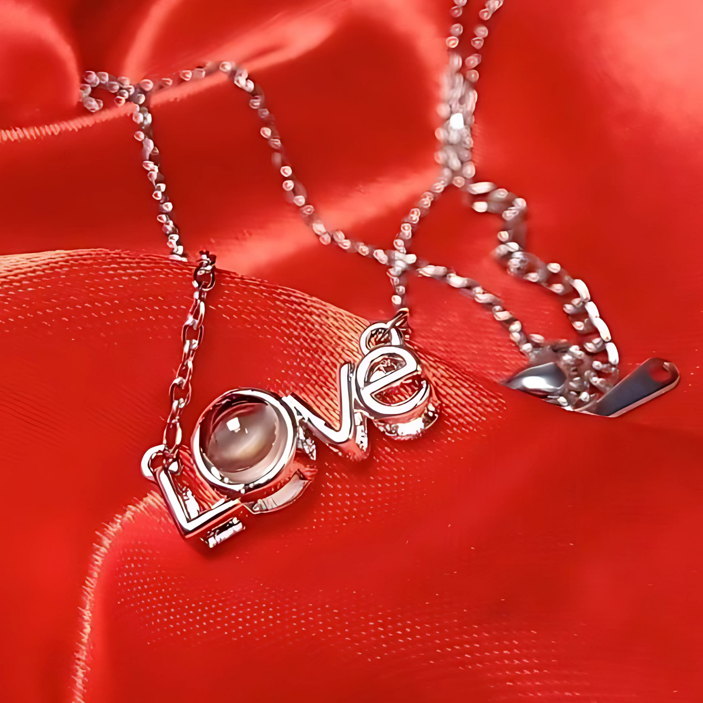 Silver necklace with 'LOVE' pendant on a red fabric background