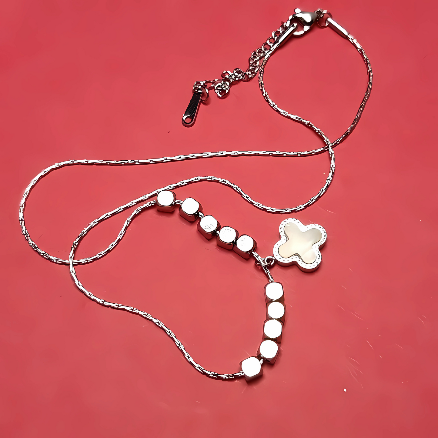 Silver necklace with a cross pendant on a red background
