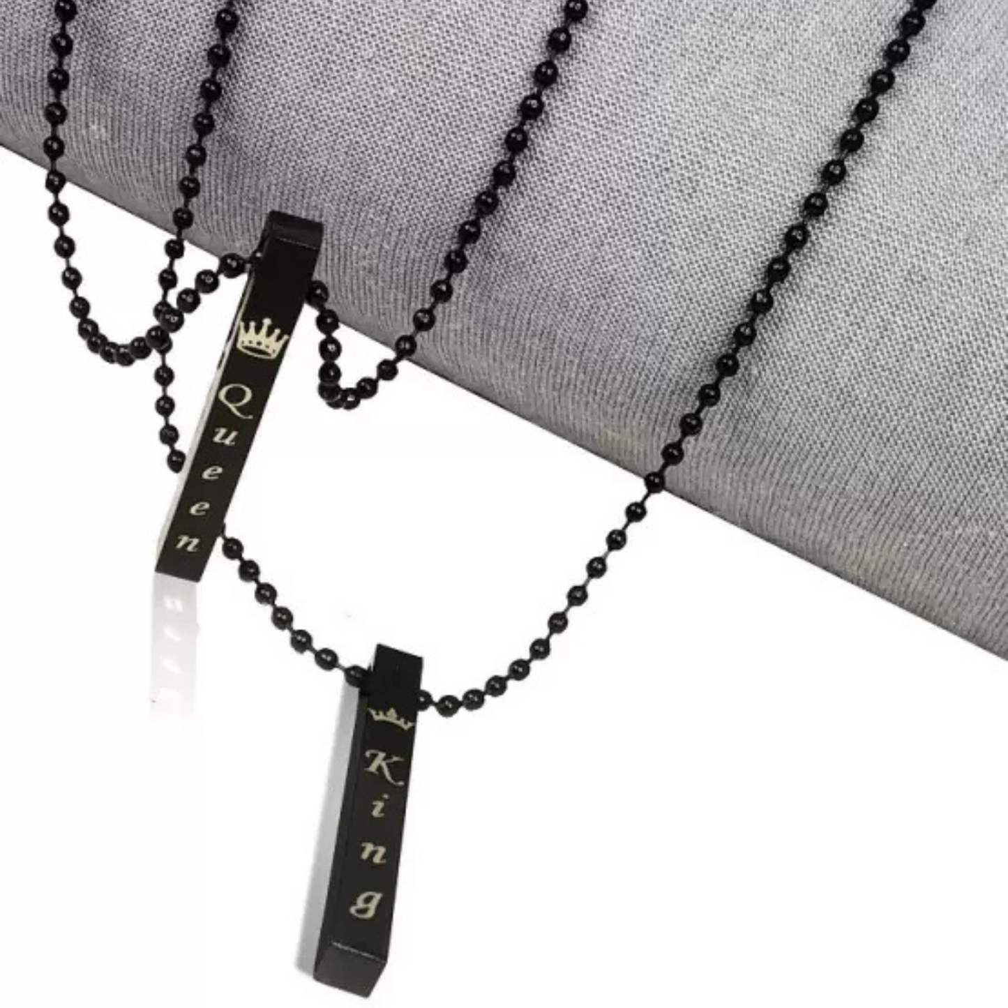 Black beaded necklaces with 'King' and 'Queen' pendants on a gray surface.