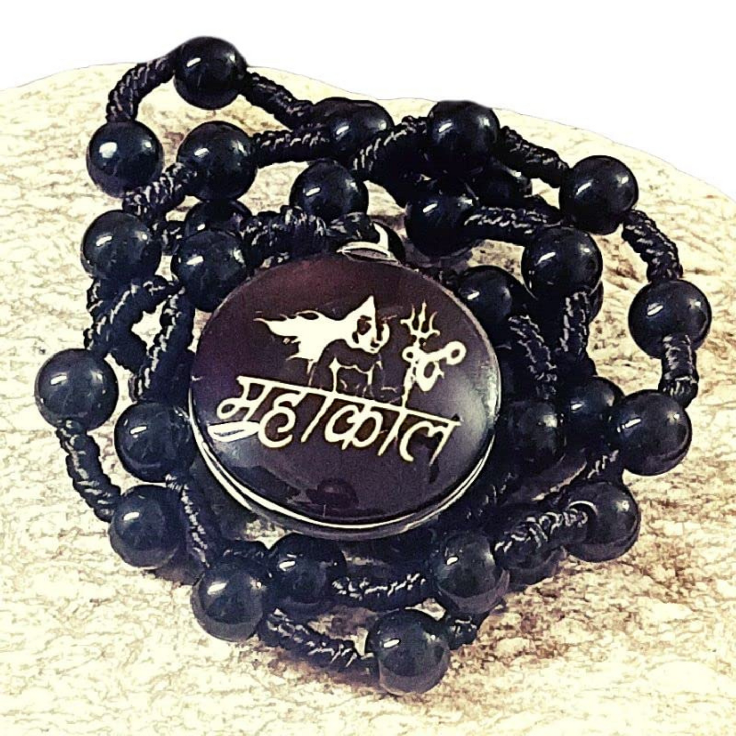 Black beaded necklace with a round black stone featuring white text and symbols on a beige background.