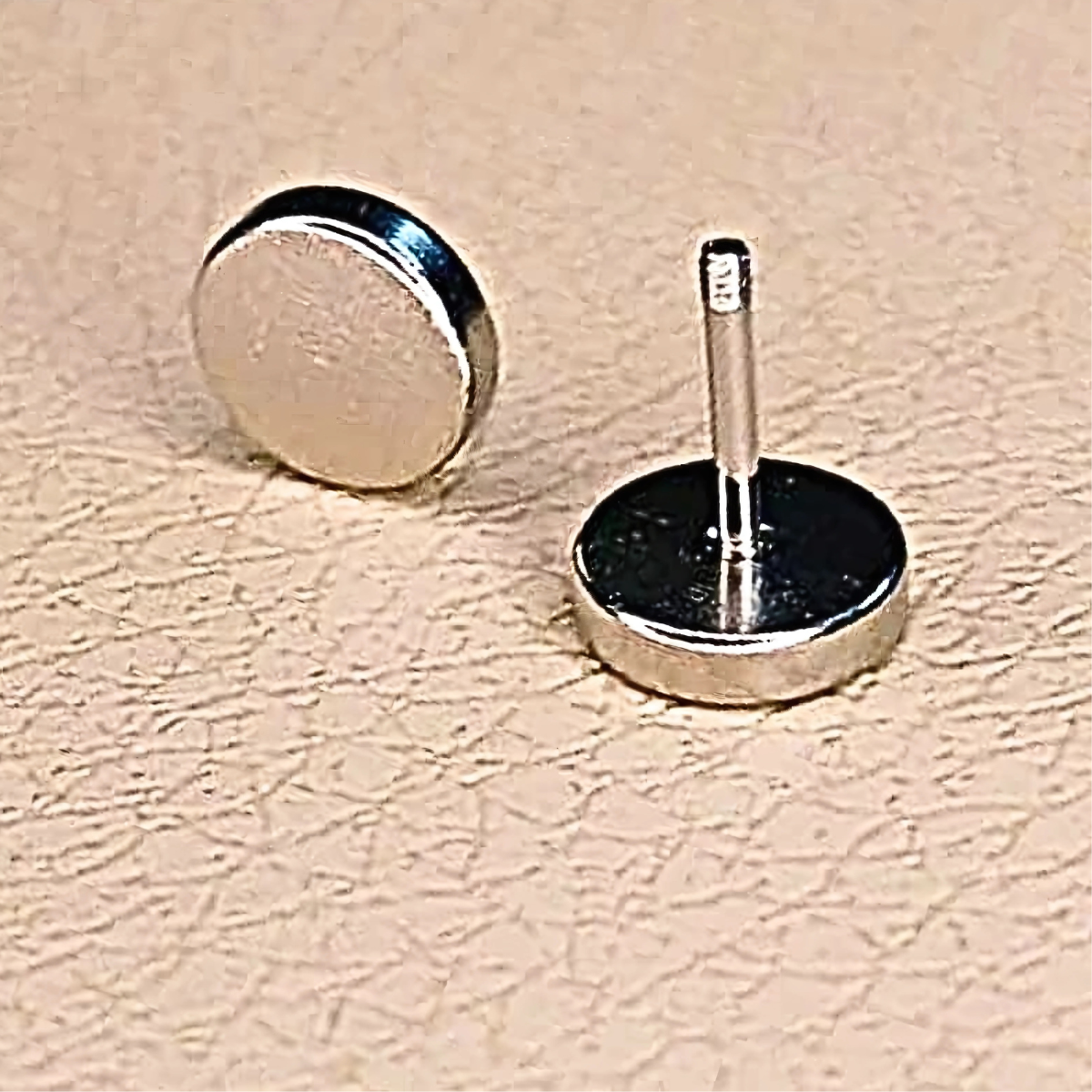 Two metallic objects on a beige textured surface