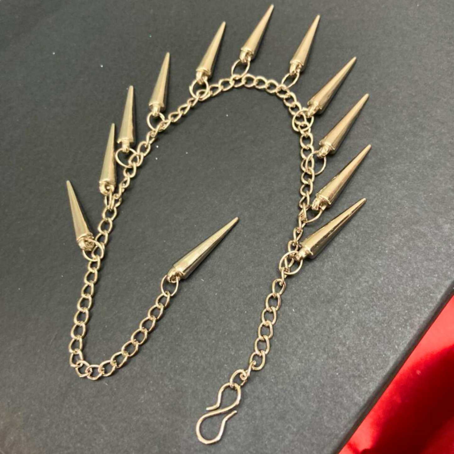 Silver chain earring with spike attachments on a dark background