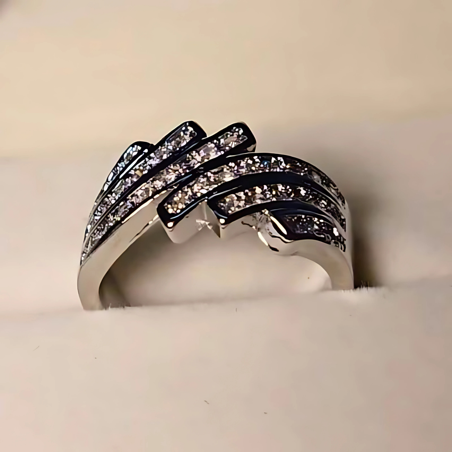 Silver ring with black and clear gemstones on a white cushion