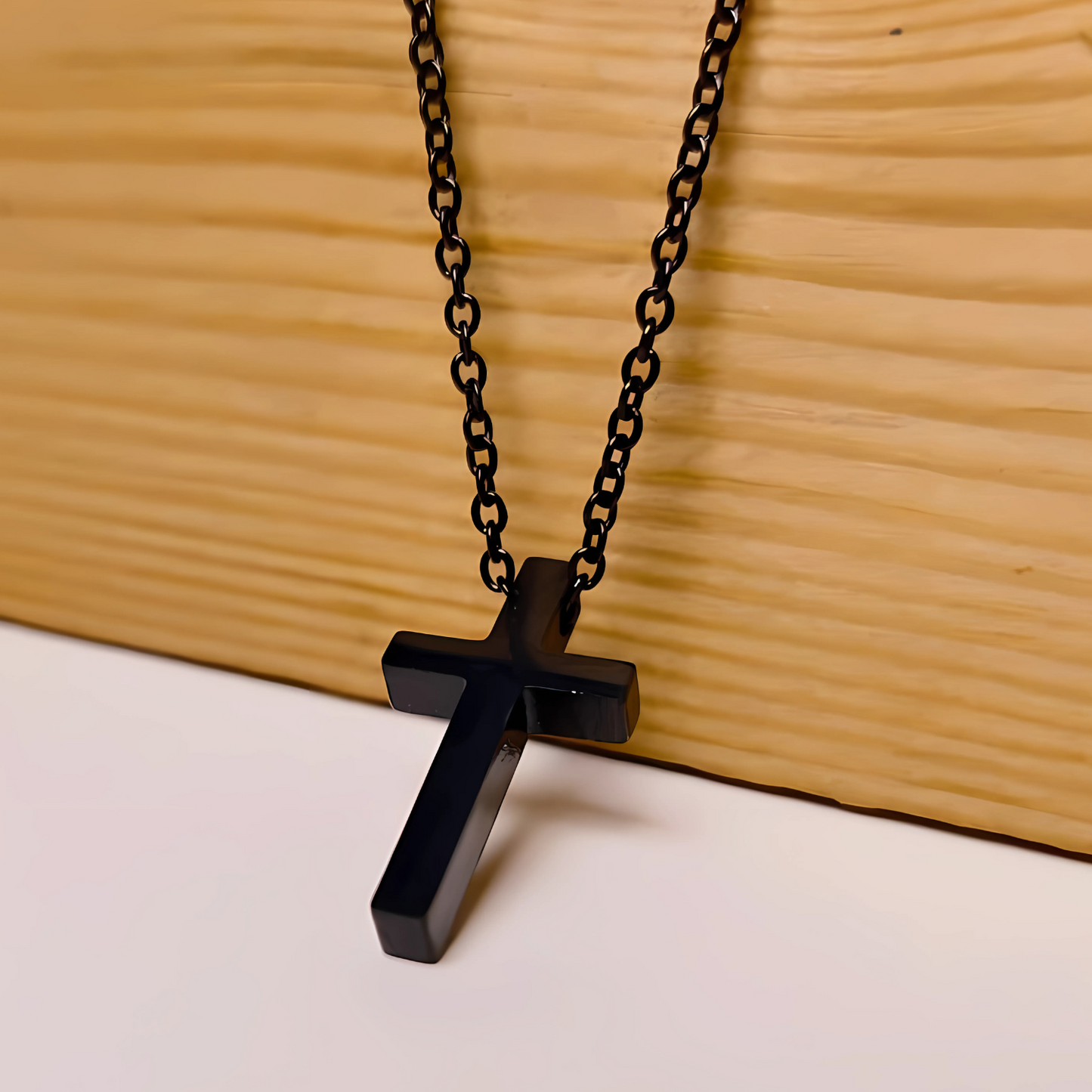 Black cross pendant necklace on a wooden surface