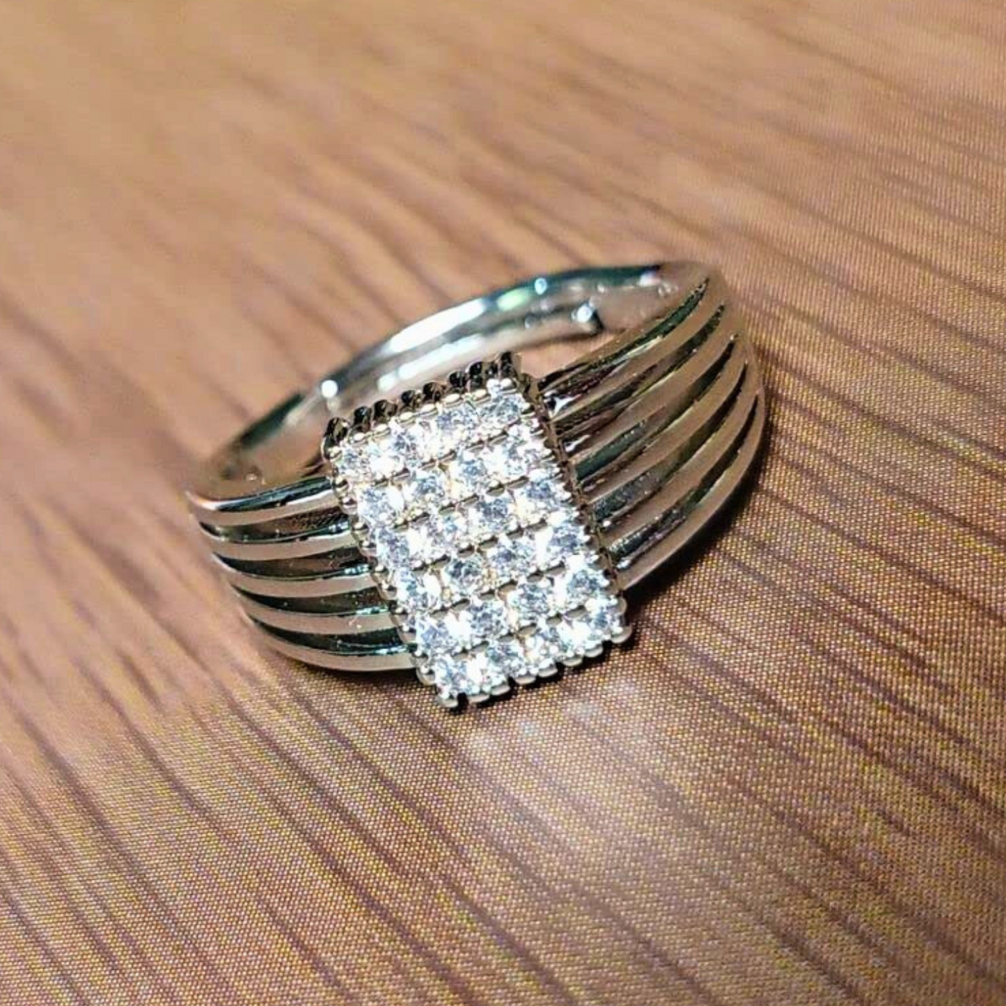 Silver ring with diamond accents on a wooden surface