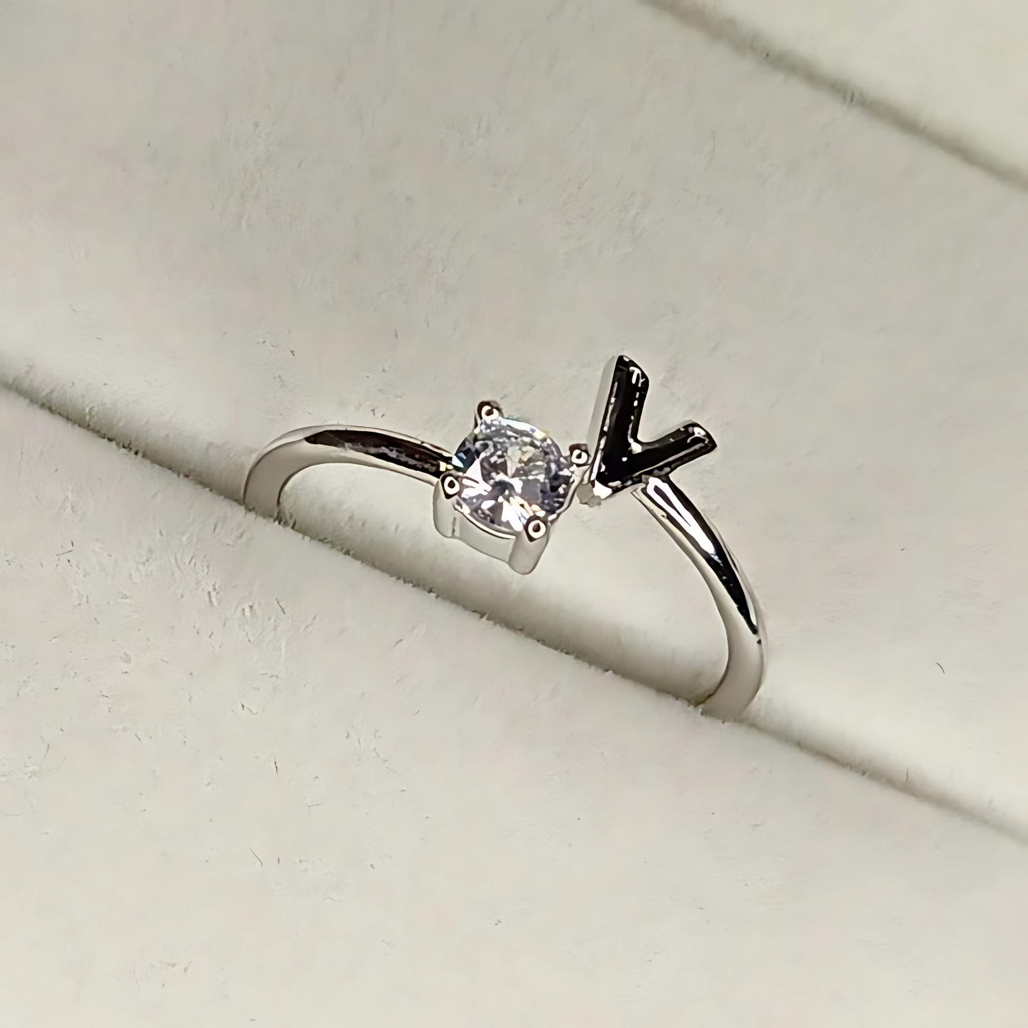 Silver ring with a diamond and black arrow design on a light gray background