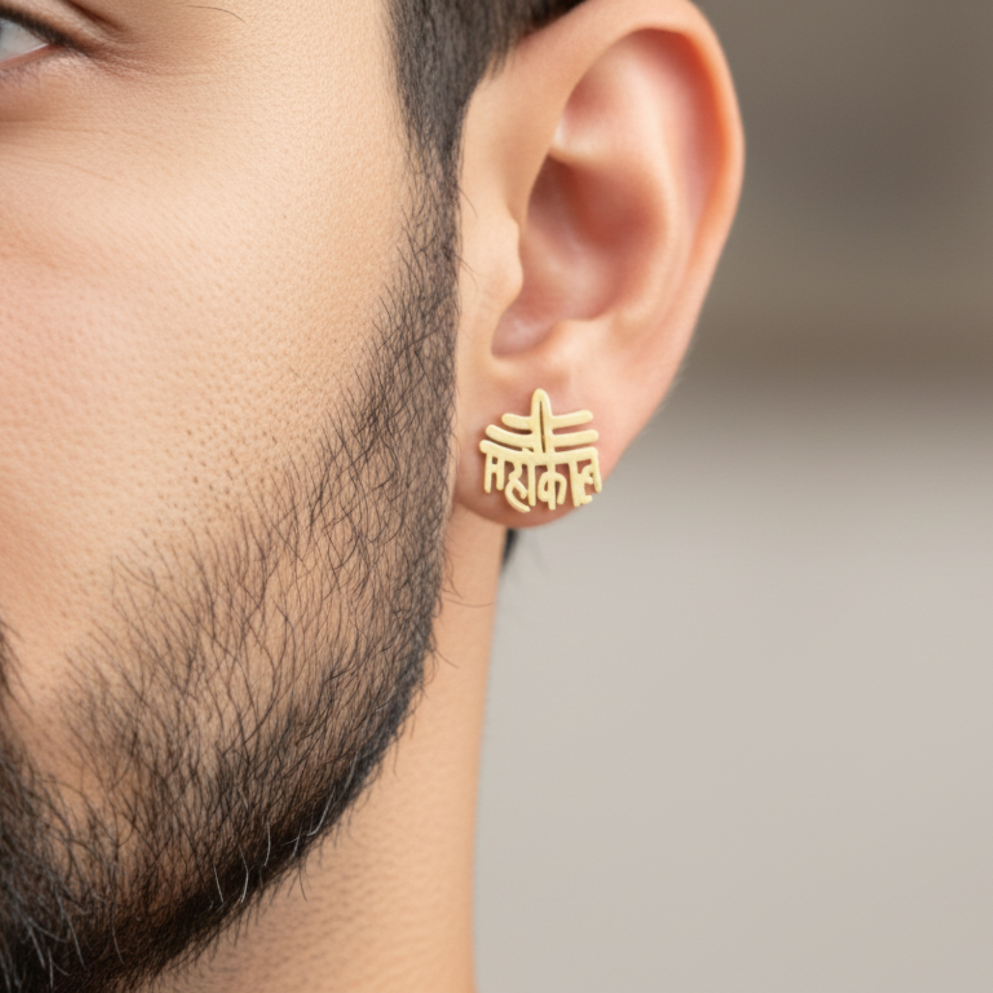 Gold earring worn by a person with a blurred background