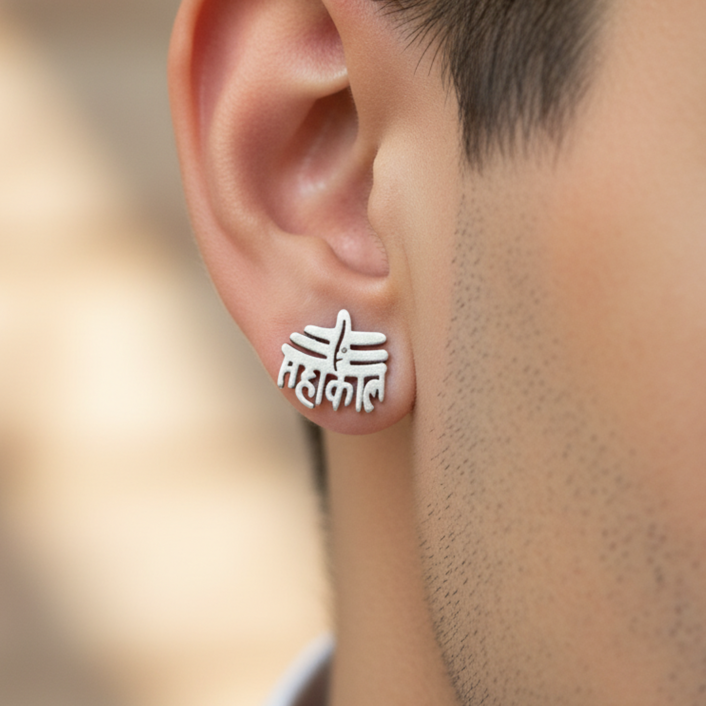 Silver earrings with a design worn by a person, against a blurred background