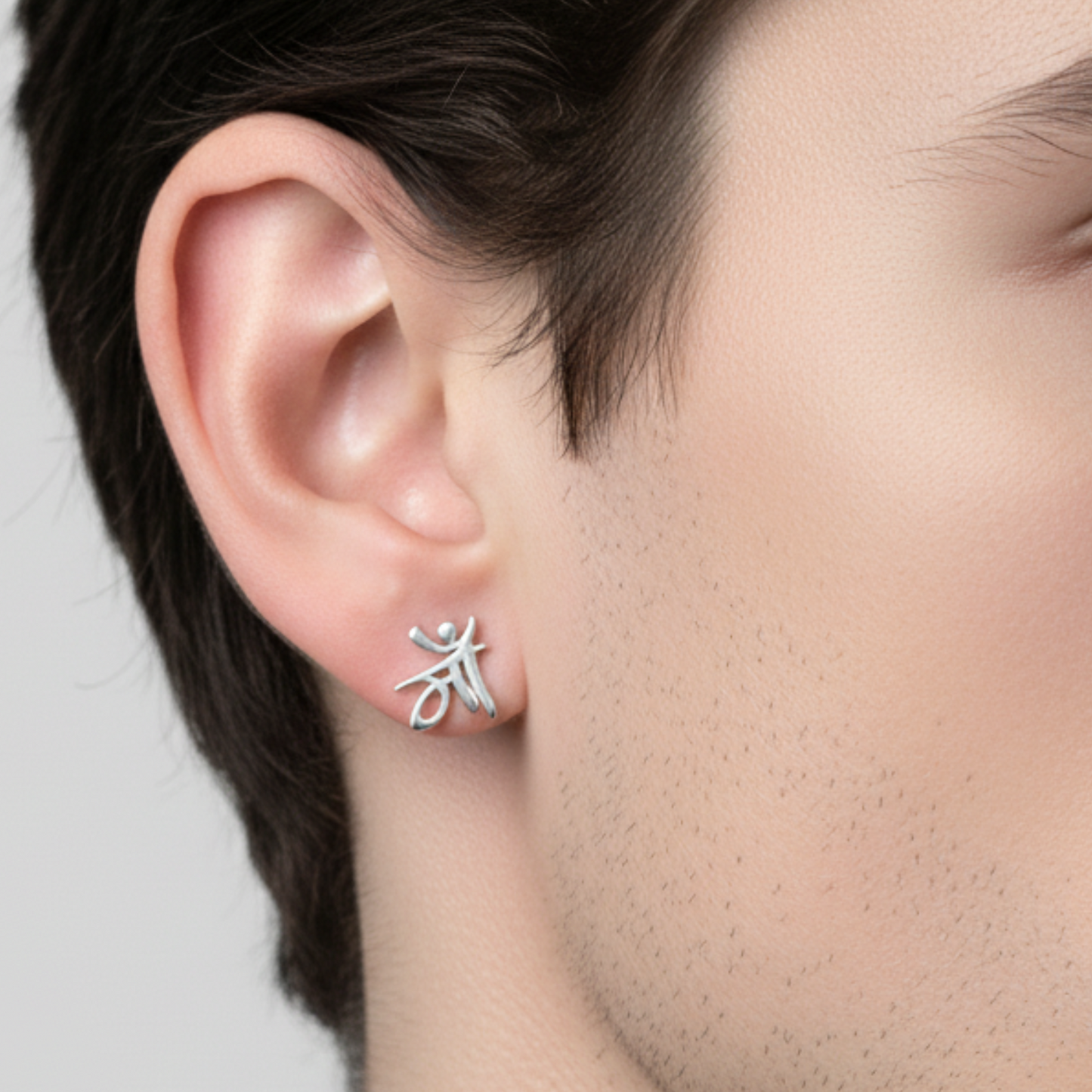 Silver earrings worn by a person with a neutral background