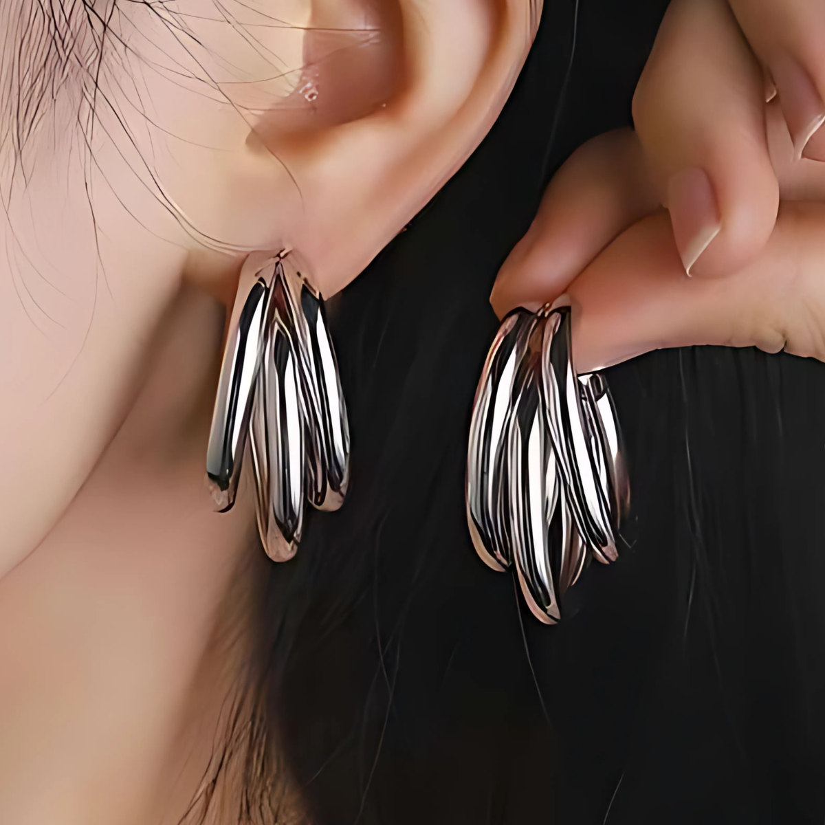 Silver hoop earrings being worn on an ear with a blurred background