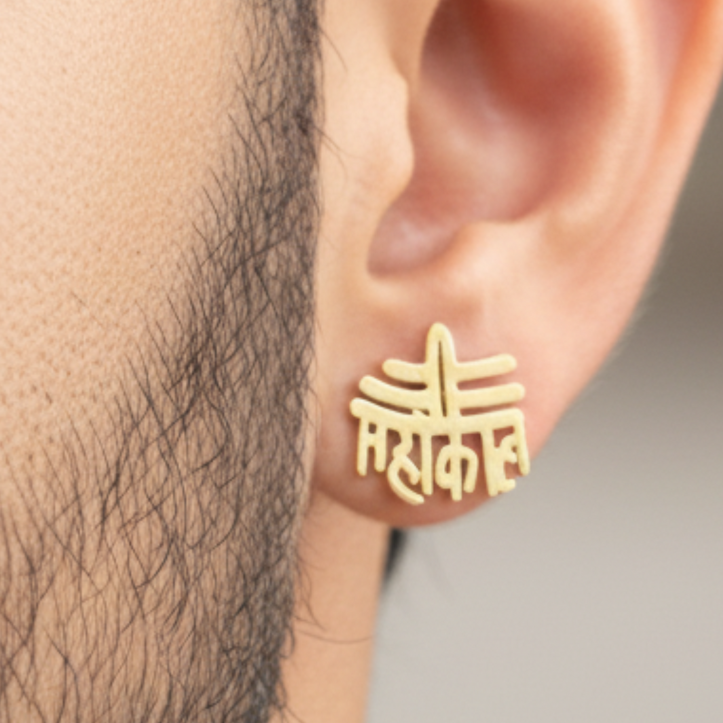 Gold ear cuff worn on an ear with a blurred background