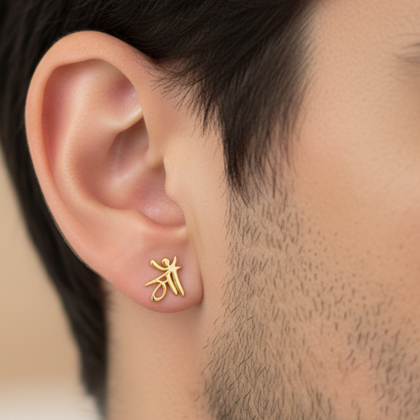 Gold earring worn on an ear with a neutral background