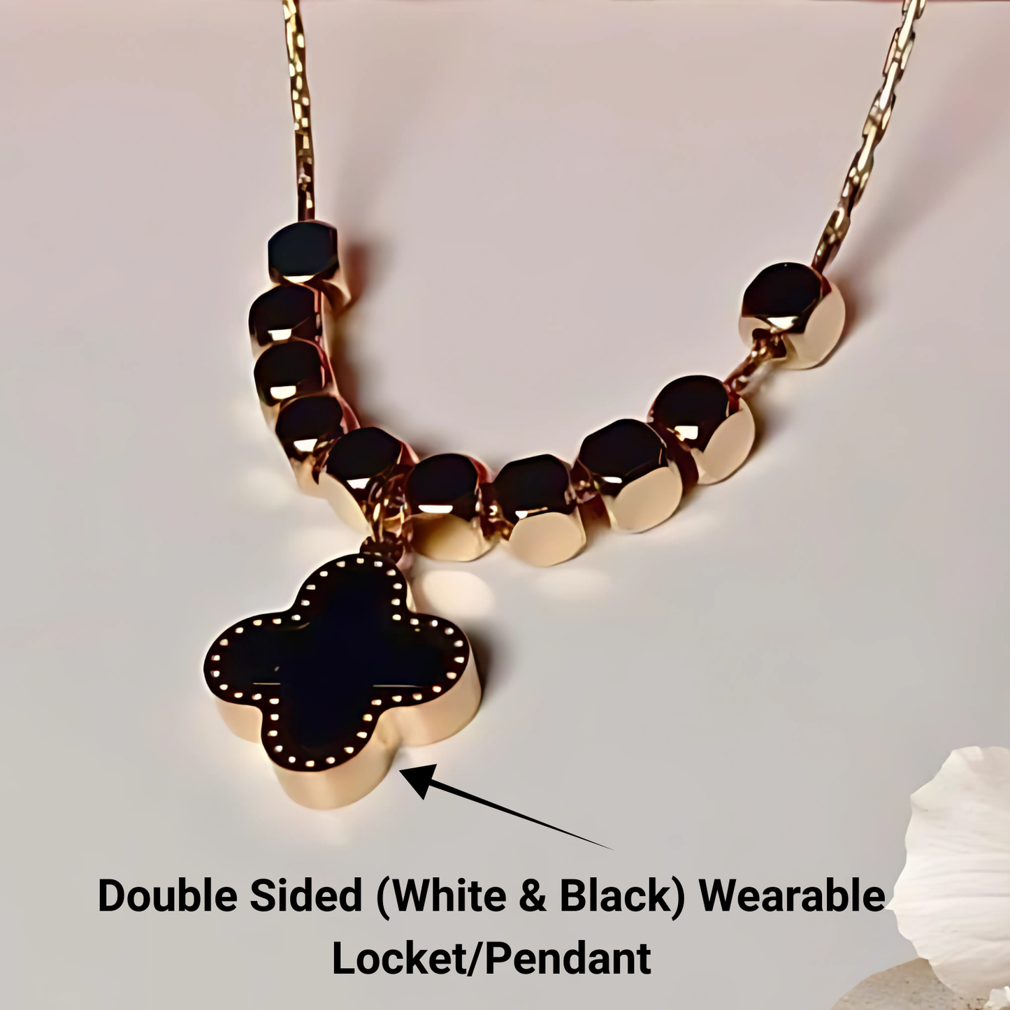 Gold necklace with a black clover-shaped pendant on a light gray background