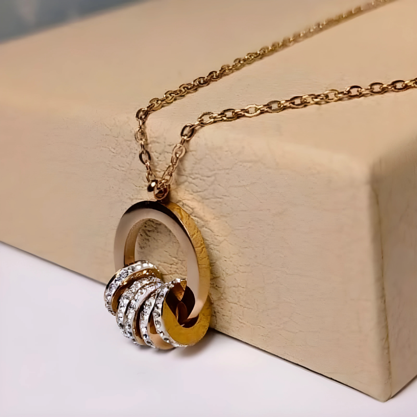 Gold necklace with a unique pendant on a beige surface