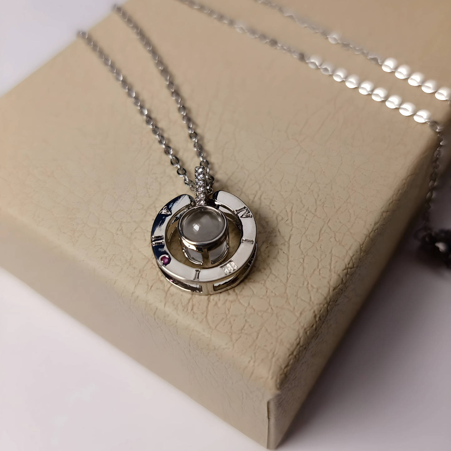 Silver necklace with a pendant on a beige box