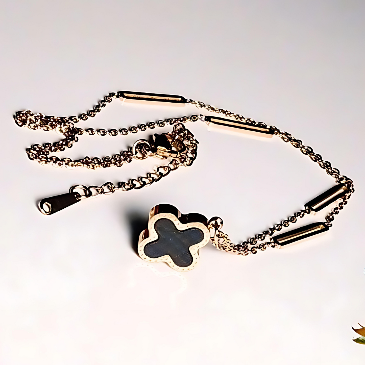 Gold chain with a clover-shaped pendant on a white background