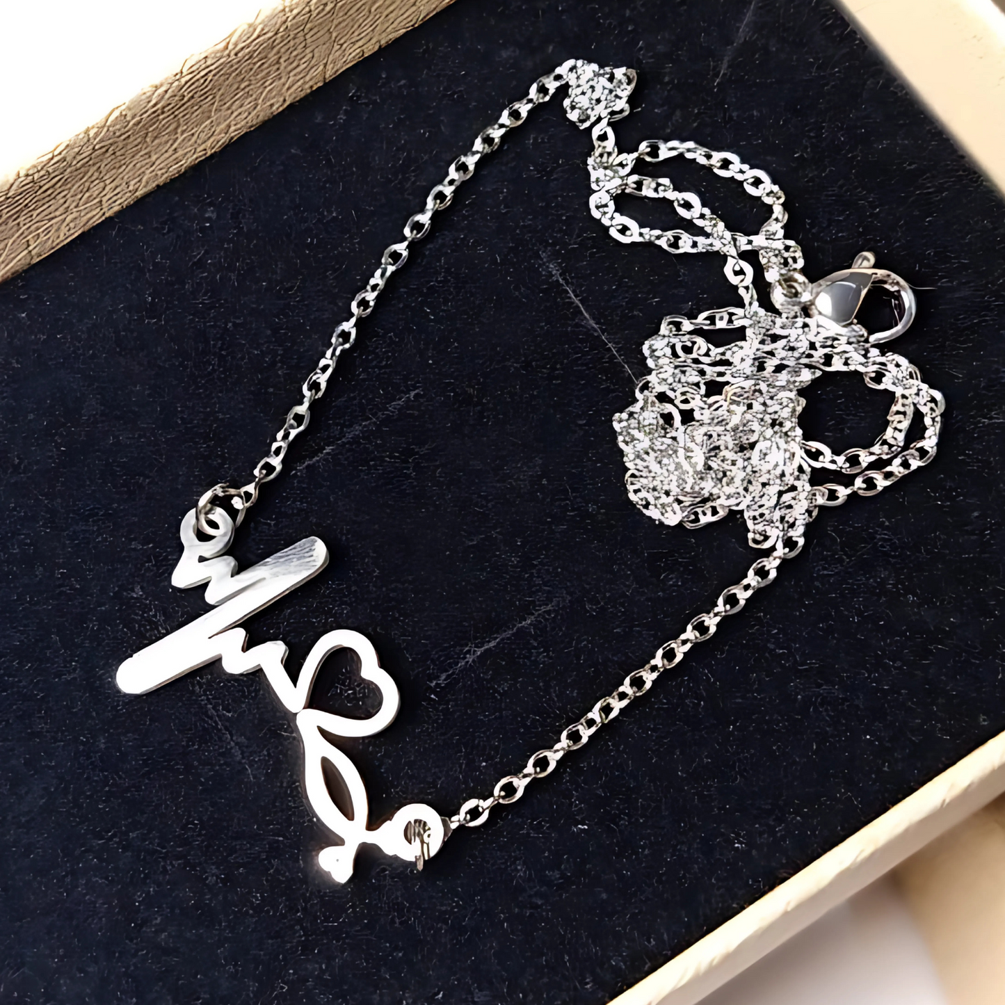 Silver necklace with heartbeat pendant on a black velvet surface
