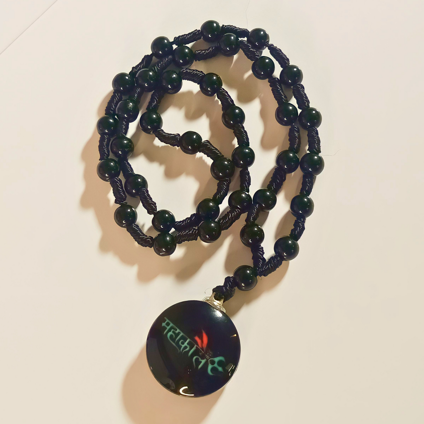 Beaded necklace with a dark pendant on a light background