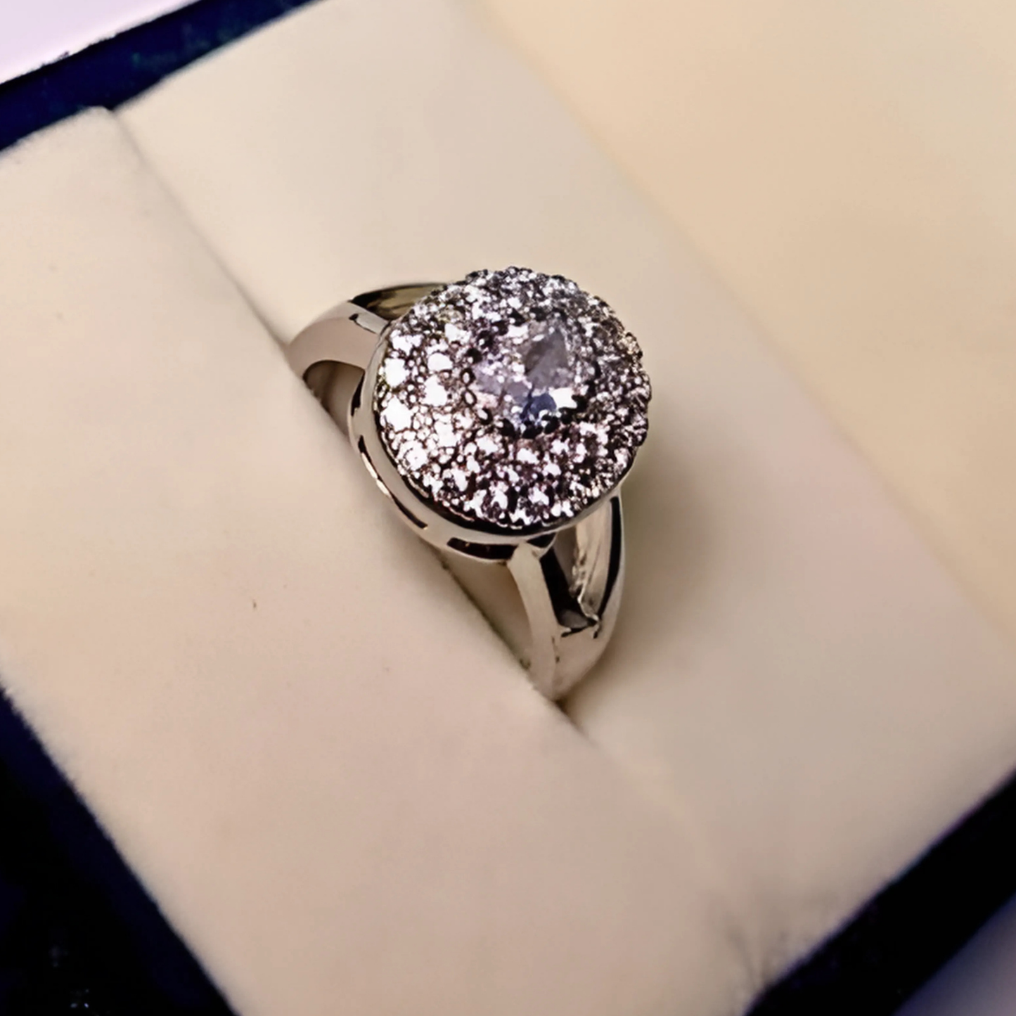Silver ring with a large diamond on a cushioned surface