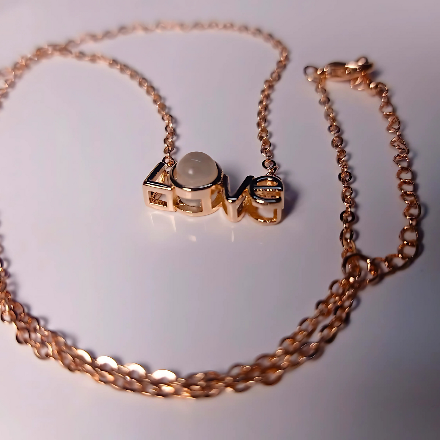 Rose gold necklace with a central pendant on a white background