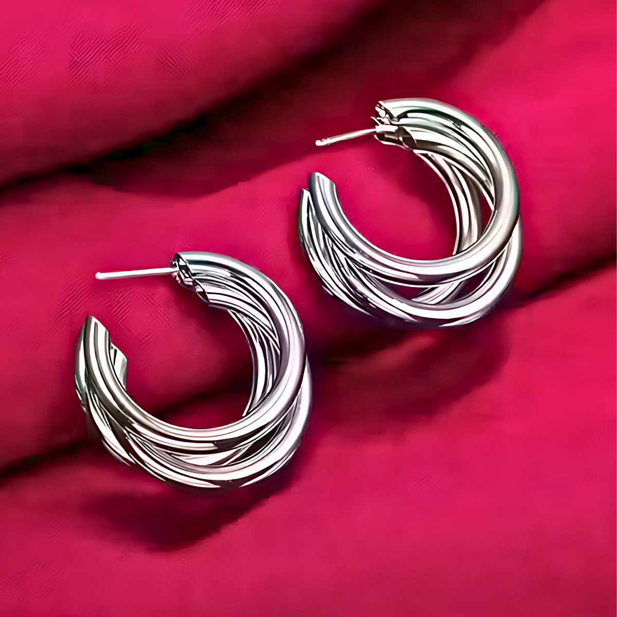 Silver hoop earrings on a red fabric background