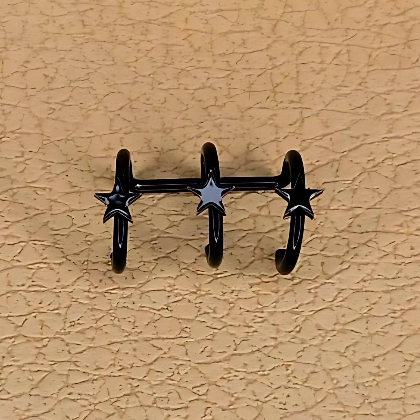 Black star-shaped wall hooks on a beige textured wall