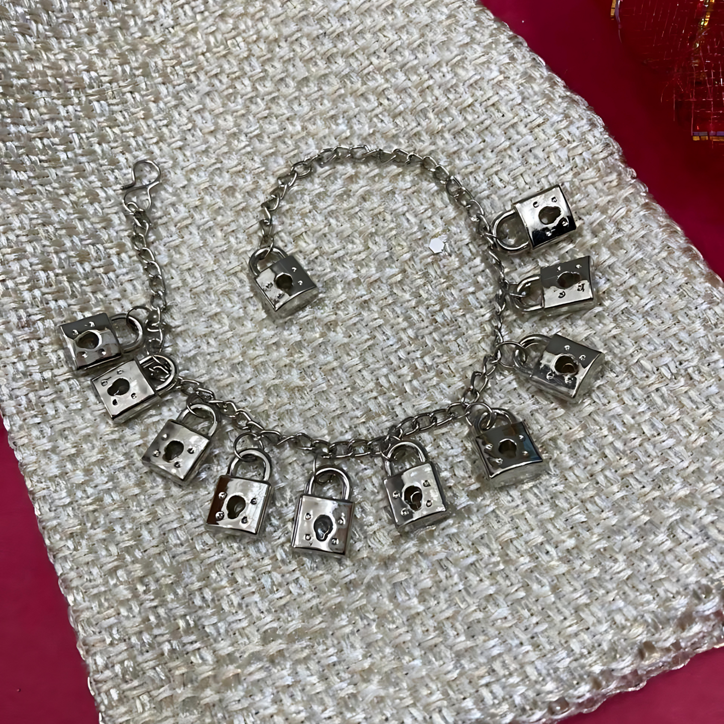 Silver bracelet with padlock charms on a textured fabric background