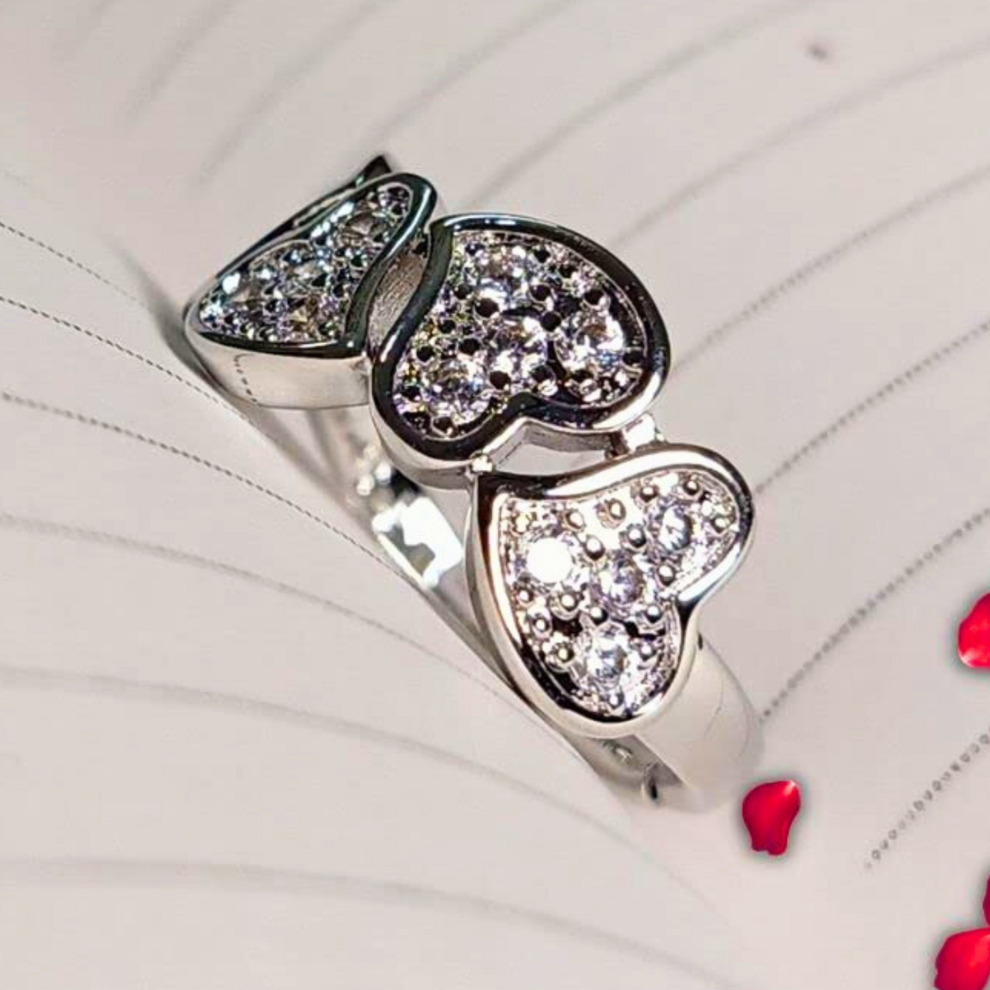 Silver ring with heart-shaped gemstones on a white background