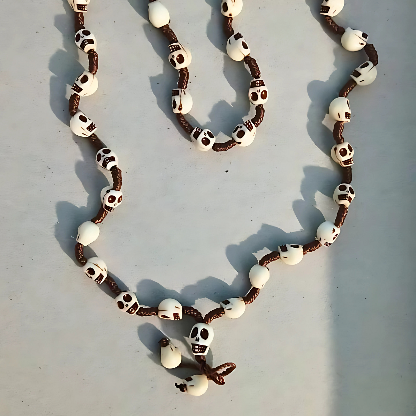 Necklace with skull and crossbones design on a light gray background
