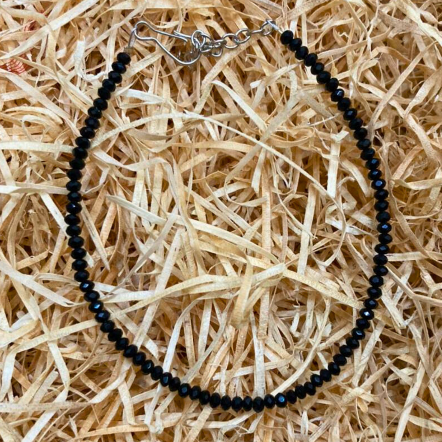 Black beaded necklace on a bed of straw