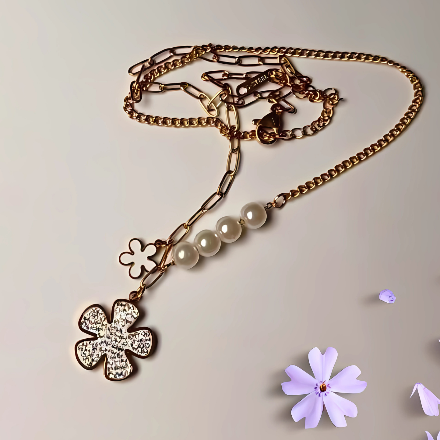 Gold necklace with floral pendants and beads on a light background