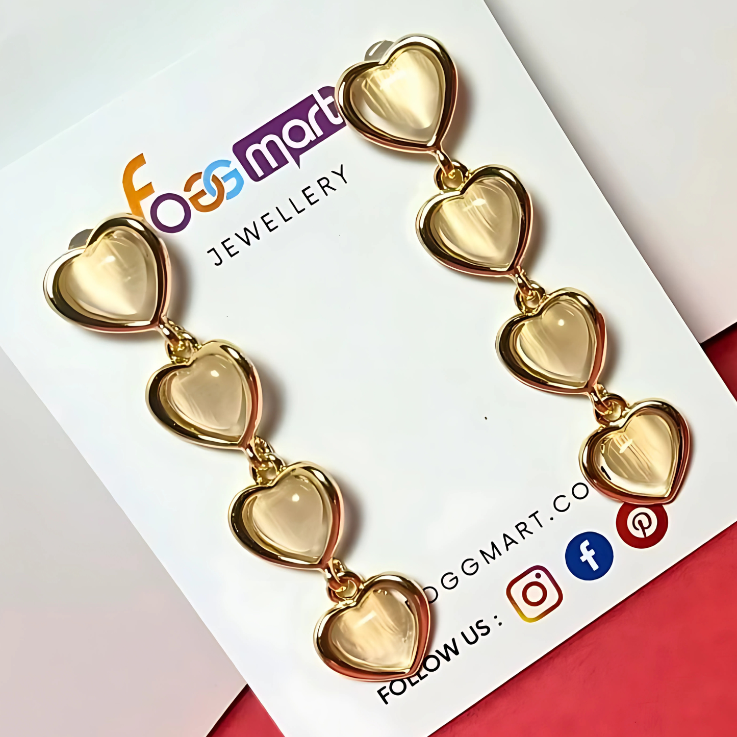 Gold heart-shaped earrings on a Foggmart Jewellery card with brand logo and social media icons.