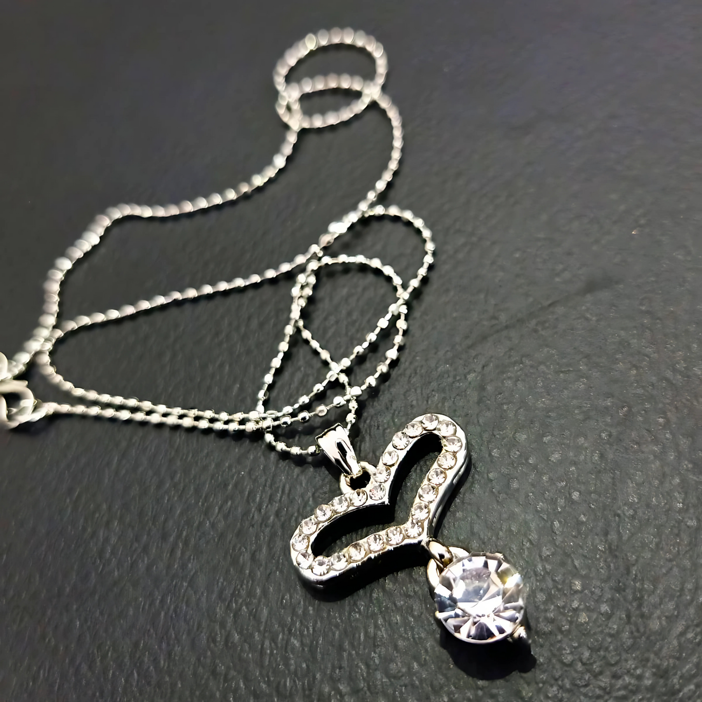 Silver necklace with a heart-shaped pendant on a dark surface