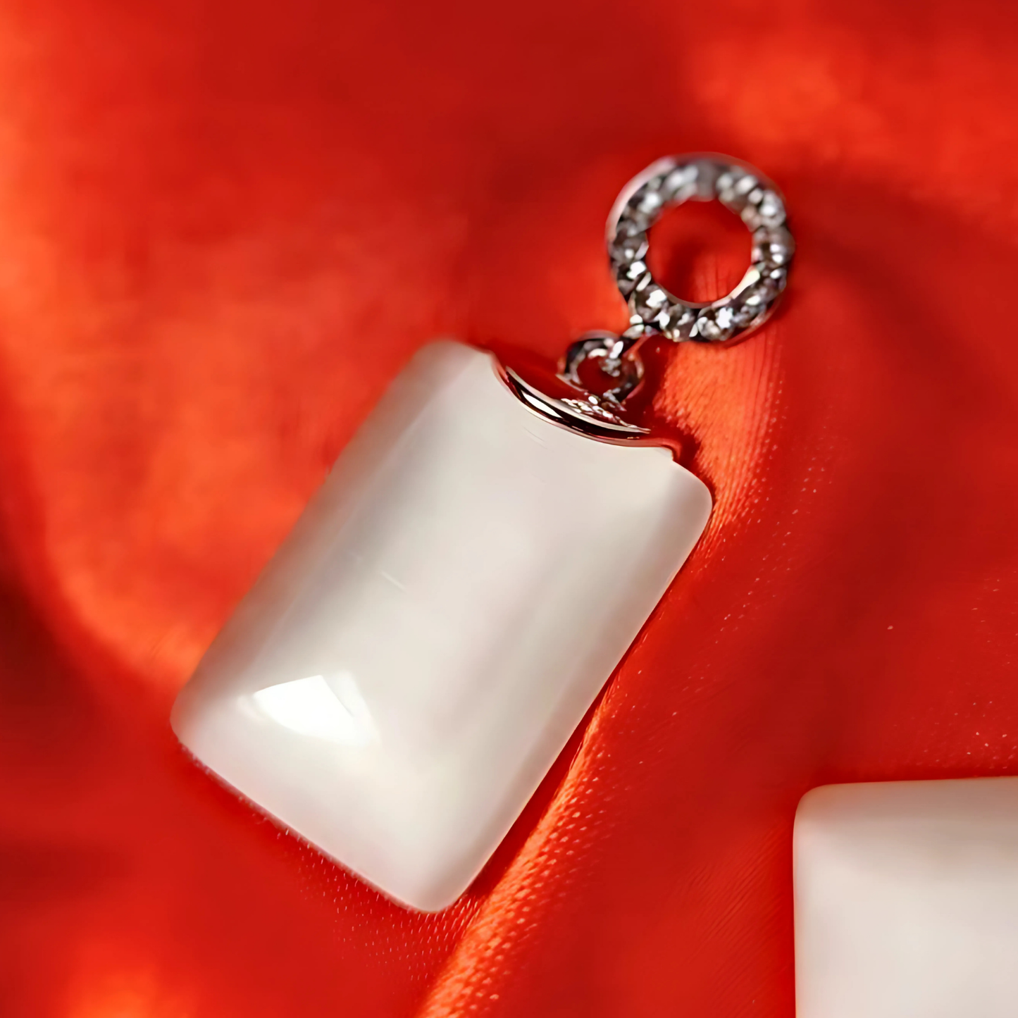 White square pendant with a silver chain on a red fabric background